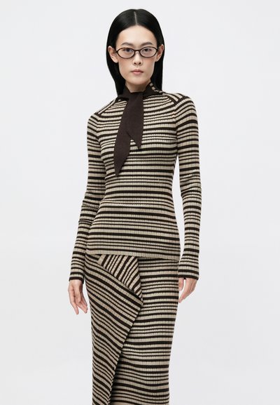 Camisola de malha riscada com gola alta e laço castanho, combinada com uma saia assimétrica correspondente. A palete de cores inclui bege e castanho escuro.