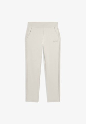 Un pantalon de survêtement gris clair en tissu doux, avec une large taille élastique et des poches latérales, présentant une marque discrète sur le devant.