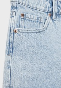 Hellblaue Jeans aus Denim mit einem verwaschenen Effekt, versehen mit kupferfarbenen Nieten und Nähten. Verfügt über eine Vordertasche und Gürtelschlaufen am Bund.