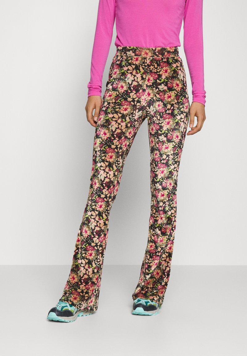 Legíny s květinovým potiskem v černé barvě s růžovými, žlutými a zelenými květy. Přiléhavé s rozšířeným lemem. Nosené s růžovým tričkem s dlouhým rukávem a teniskami.