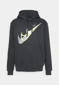 Sudadera negra de Nike con un gran gráfico del swoosh reflectante en gris y amarillo neón. Cuenta con un bolsillo frontal y capucha ajustable con cordón.