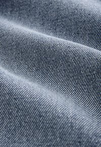 Gros plan sur un tissu rayé bleu et blanc avec une texture douce et ondulée montrant les détails fins du tissage.