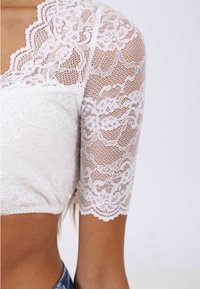 Vit spetsoberdel med korta ärmar, blommönster, en scalloped halsringning och en texturerad byst. Designen är åtsittande och kort.