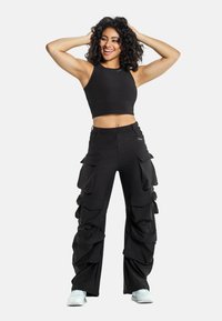 Musta lyhythihainen croptop, jossa on matching mustat cargo-housut, joissa on useita poimutettuja taskuja, rento mitoitus ja sileä kangas.
