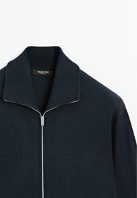 Maglione zip-up di un blu navy scuro con un alto colletto a coste, realizzato in morbido materiale, con una cerniera di colore argento e un'etichetta con "Massimo Dutti."