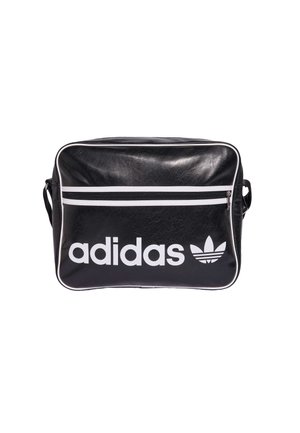 Sac à bandoulière noir Adidas avec passepoils blancs, poche avant zippée, et grand logo Adidas blanc avec trèfle à l’avant.