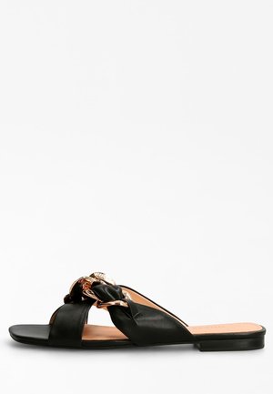 Sandalo infradito in pelle nera con cinturini intrecciati e dettaglio in tono oro. Suola piatta, design minimalista e texture liscia.