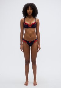 Czarny koronkowy biustonosz i pasujący do niego bikini z czerwonymi kwiatowymi haftami, misternymi wzorami, regulowanymi ramiączkami i kokardką na pasku.