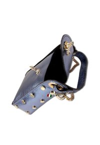 Blauwe leren handtas met gouden studs en hardware, voorzien van een kettingband en vlinderaccent, geopend vanuit een driehoekige vorm.