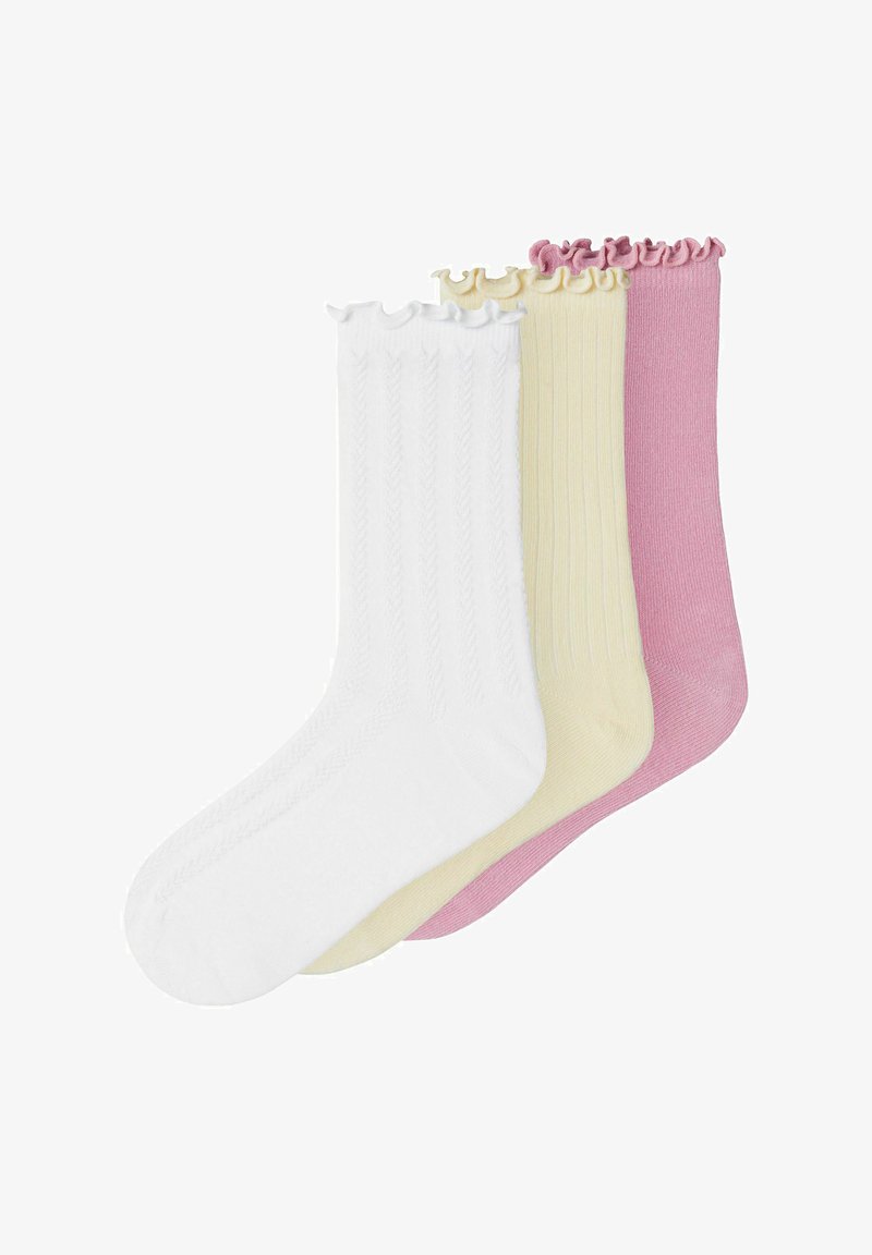Trois paires de chaussettes à volants, en blanc, jaune pâle et rose, superposées sur un fond blanc.