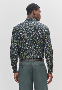 Langærmet skjorte med mørk marineblå baggrund, med blomster- og citrusmønstre i grøn, gul og hvid. Slank pasform, med krave.