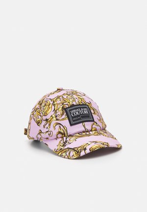 Roze baseballpet met gouden barokpatroon en een zwart rechthoekig label met opschrift Versace Jeans Couture aan de voorkant.