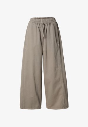 Bézs színű, bőszárú nadrág gumis derékrésszel és húzózsinórral, oldalvarrásos részletekkel és laza szabással.