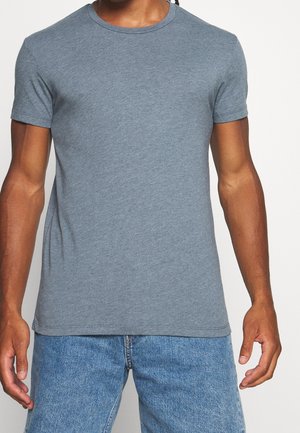 Gray short-sleeve T-shirt made of soft cotton, featuring a round neckline and a slim fit, partially tucked into blue jeans.