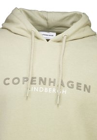 Felpa color beige chiaro con cappuccio regolabile e stampa del testo "COPENHAGEN" in grigio e "LINDBERGH" in bianco. Tessuto morbido.