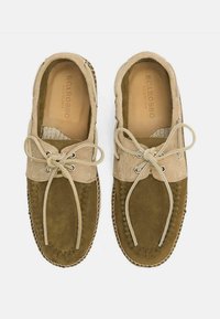 Zapatos de ante marrón con detalles de cuero beige, presentan una puntera redonda, costuras decorativas y cierre de cordones. El forro interior es de cuero marrón claro.