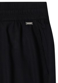 Pantalon noir à taille élastique avec poche sur la couture latérale et petite étiquette métallique rectangulaire de la marque au-dessus de la poche.