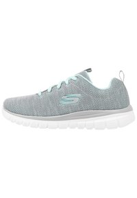 Baskets en maille grises avec des lacets et un logo bleu clair. Elles présentent une semelle blanche rembourrée et une languette au talon pour un enfiler facile.