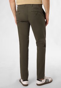 Olivgrüne Chinos mit geradem Bein, ausgestattet mit zwei Gesäßtaschen und dezenten Steppdetails, kombiniert mit weißen Sneakers.