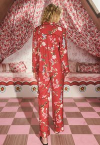 Set de pijamale cu imprimeu floral roșu, cu mâneci lungi și pantaloni, cu păsări și flori. Material neted, croială lejeră și accente negre.