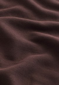 Tela marrón oscura con una superficie lisa y texturizada, con suaves ondas fluidas y un patrón de tejido consistente.