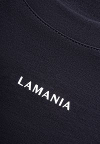 Czarny bawełniany T-shirt z prążkowanym okrągłym dekoltem i białym napisem "LAMANIA" nadrukowanym ukośnie na piersi.