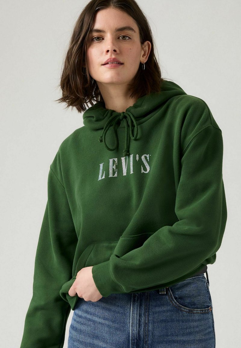 Grön hoodie i mjuk bomull med snörad huva. Har en stor silverfärgad "LEVI'S"-logotyp på bröstet och en framficka.