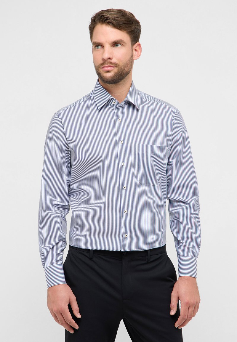 Blauw-wit gestreept overhemd met knoopsluiting aan de kraag, een borstzak en lange mouwen, gecombineerd met een donkere broek.