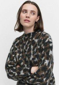Stickad tröja i brunt, svart och grått leopardmönster. Tillverkad av ett mjukt, fluffigt material med rund halsringning och långa ärmar.