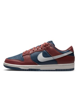 Baskets basses en cuir rouge et marine avec un logo Nike blanc et une semelle intermédiaire blanche, vues de côté sur fond blanc.