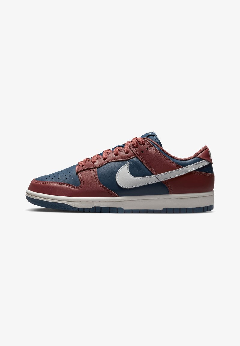 Baskets basses en cuir rouge et marine avec un logo Nike blanc et une semelle intermédiaire blanche, vues de côté sur fond blanc.
