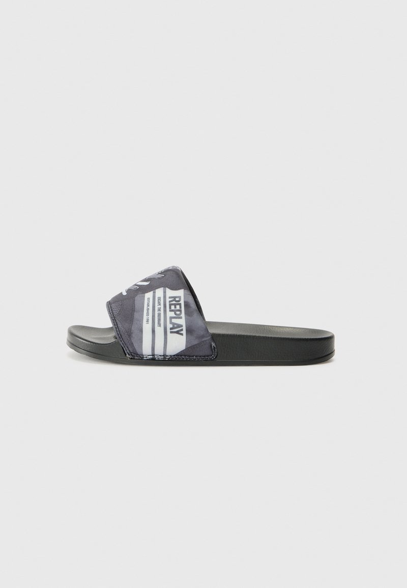 Sort slide sandal med en stofrem, der har et gentaget hvidt logo og grafisk print, flad sål, glat tekstur og minimalistisk design.
