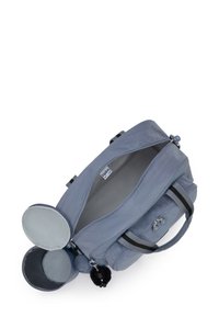 Grå duffelbag med en lynlås, to sidelommer og et fluffy vedhæng. Har dobbelte håndtag og en foret indvendig del med et mærke-logo.