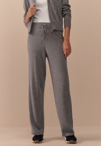 Gray, lightweight, knit sweatpants with a drawstring waistband and ankle cuffs. Paired with a white top and dark sneakers.