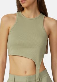 Olivově zelený žebrovaný cropped top bez rukávů s zakřiveným lemem a bočním výřezem. Tkanina vypadá hladce a má pružnost pro pohodlí.