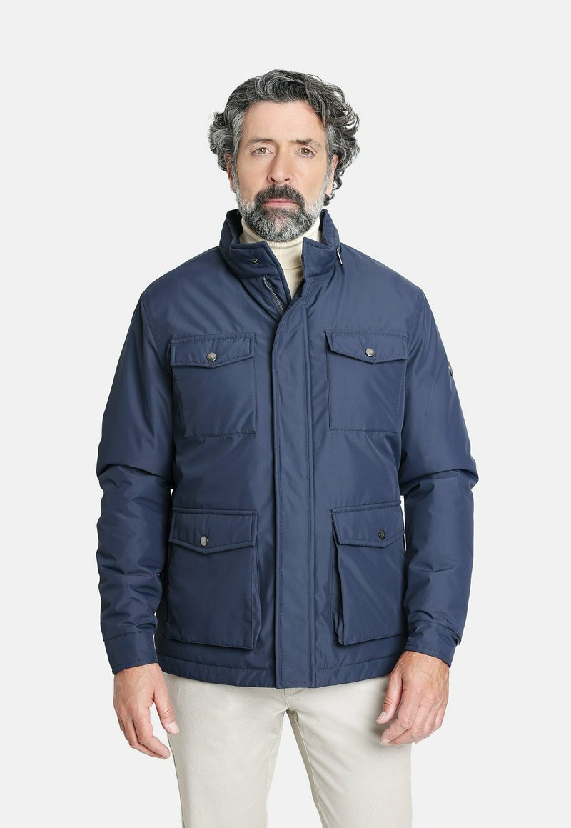 Chaqueta aislante azul marino con cuello alto, dos bolsillos en el pecho y dos bolsillos laterales; textura suave con cierres de botones.