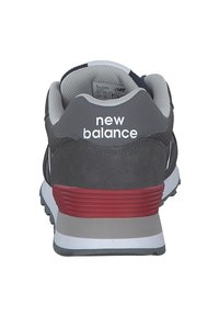 Graue Sneaker mit Obermaterial aus Wildleder und Mesh, weißem "New Balance"-Logo, roten Akzenten an der Ferse und einem gepolsterten Kragen für zusätzlichen Komfort.