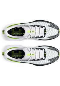 Chaussures de sport blanches et noires avec une tige en mesh, accents verts, design texturé et lacets. Présentant un logo sur la semelle intérieure.