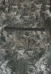 Textured fabric with a floral pattern in shades of gray and brown, featuring a black trim along a single pocket.