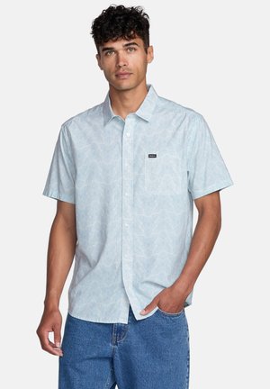 Short-sleeve, light blue button-up shirt with a subtle wave pattern, featuring a chest pocket and a logo patch on the left side.