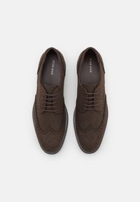 Brune semskede oxfordsko med rund tå, brogue-detaljer og flad snøringslås. Glat struktur og gummisål.