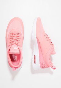 Nike-sneakers i ljusrosa med mesh och syntetiska överdrag, rundad tå, snörning och vit gummisula med en luftenhet.