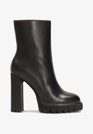 Zwarte leren enkellaars met een gladde afwerking, vierkante hoge hak en gestructureerde zool, met een chunky ontwerp en ronde neus.