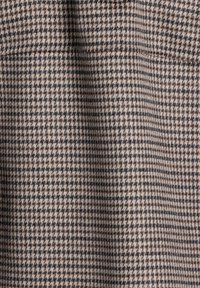 Tissu pied-de-poule marron et beige avec une texture douce, composé de motifs entrelacés noir et marron clair.