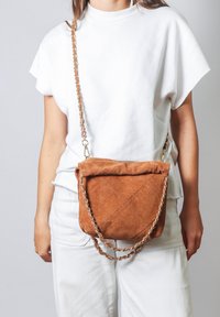 Borsa a tracolla in suede marrone con tracolla a catena intrecciata e texture trapuntata, caratterizzata da un design a patta.