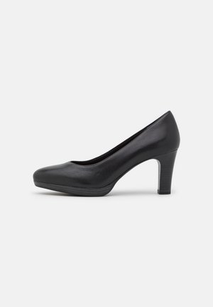 Chaussure à talon haut en cuir noir avec un bout arrondi, une surface lisse, et un talon bloc de hauteur moyenne présentant un léger éclat et des coutures discrètes.