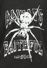 Egy fehér pók grafika középen, a háttérben megkopott szöveggel: "MINDIG HŰ ÉS TISZTÍTOTT" sötét textil háttéren.