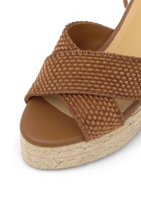Sandale à bride tressée marron avec design croisé, semelle intérieure couleur cuir et plateforme espadrille tressée.