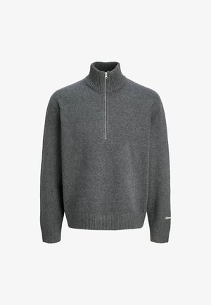 Szary sweter dzianinowy z wysokim kołnierzem i pół-zamkiem, w połączeniu z luźnymi beżowymi spodniami i szarymi butami sportowymi. Akcenty na mankietach.