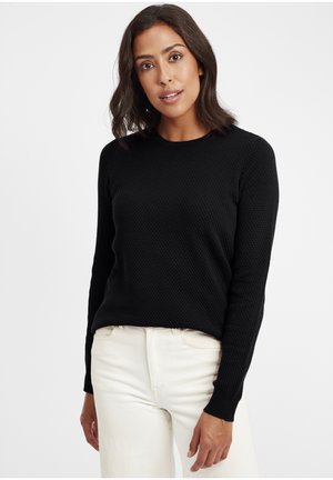 Maglione nero, con texture, a girocollo e maniche lunghe, abbinato a jeans chiari e aderenti. Tessuto liscio con un motivo in rilievo.